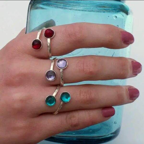 lady's hand holding a clear jar-3 silver rings with 2 stones each