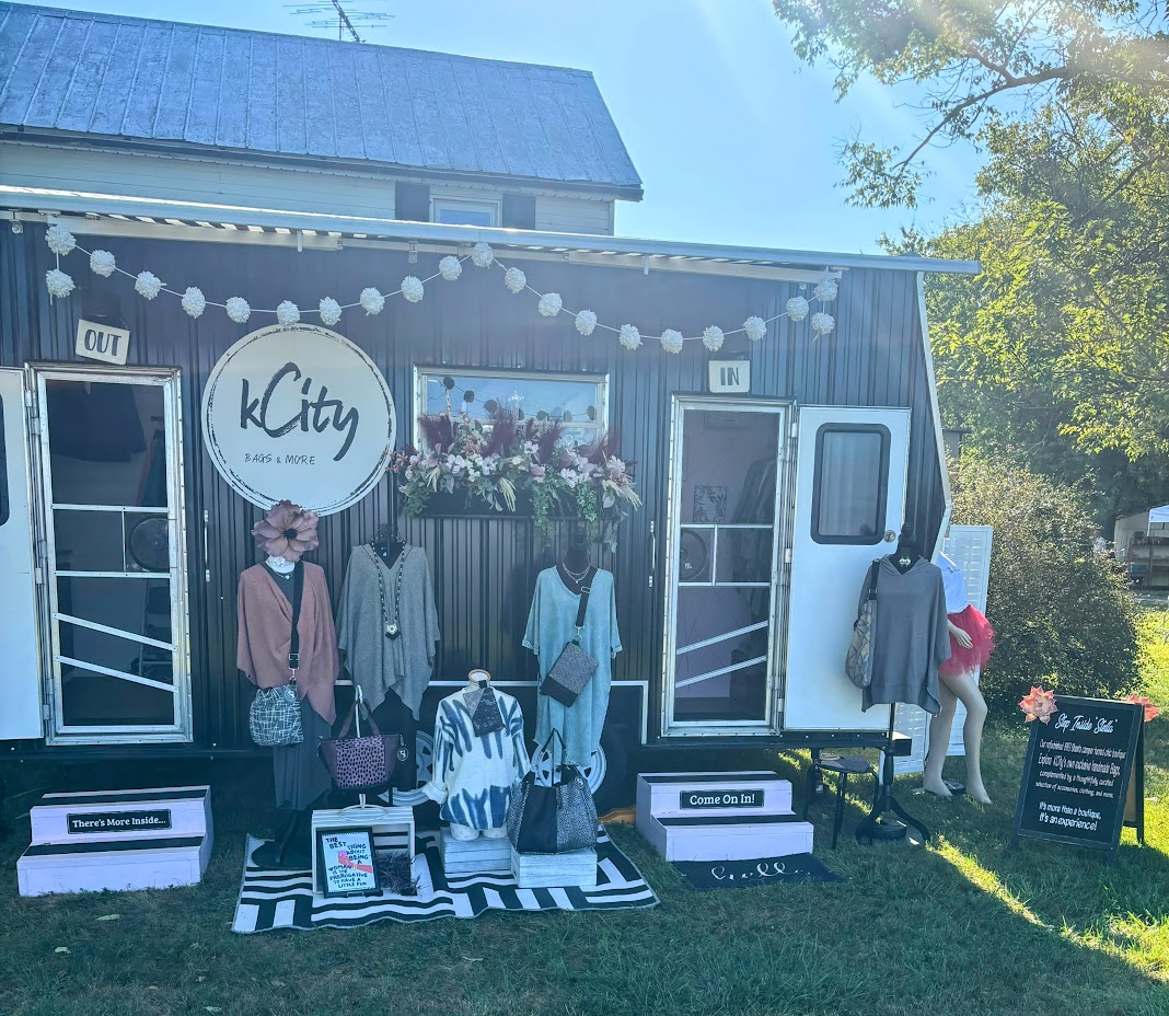 Black tailer with clothing mannequins and window box with flowers out front.